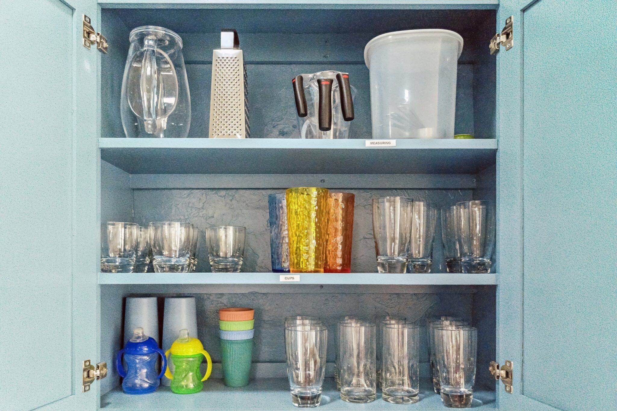 Un armario de cocina con cristalería y utensilios de medición.