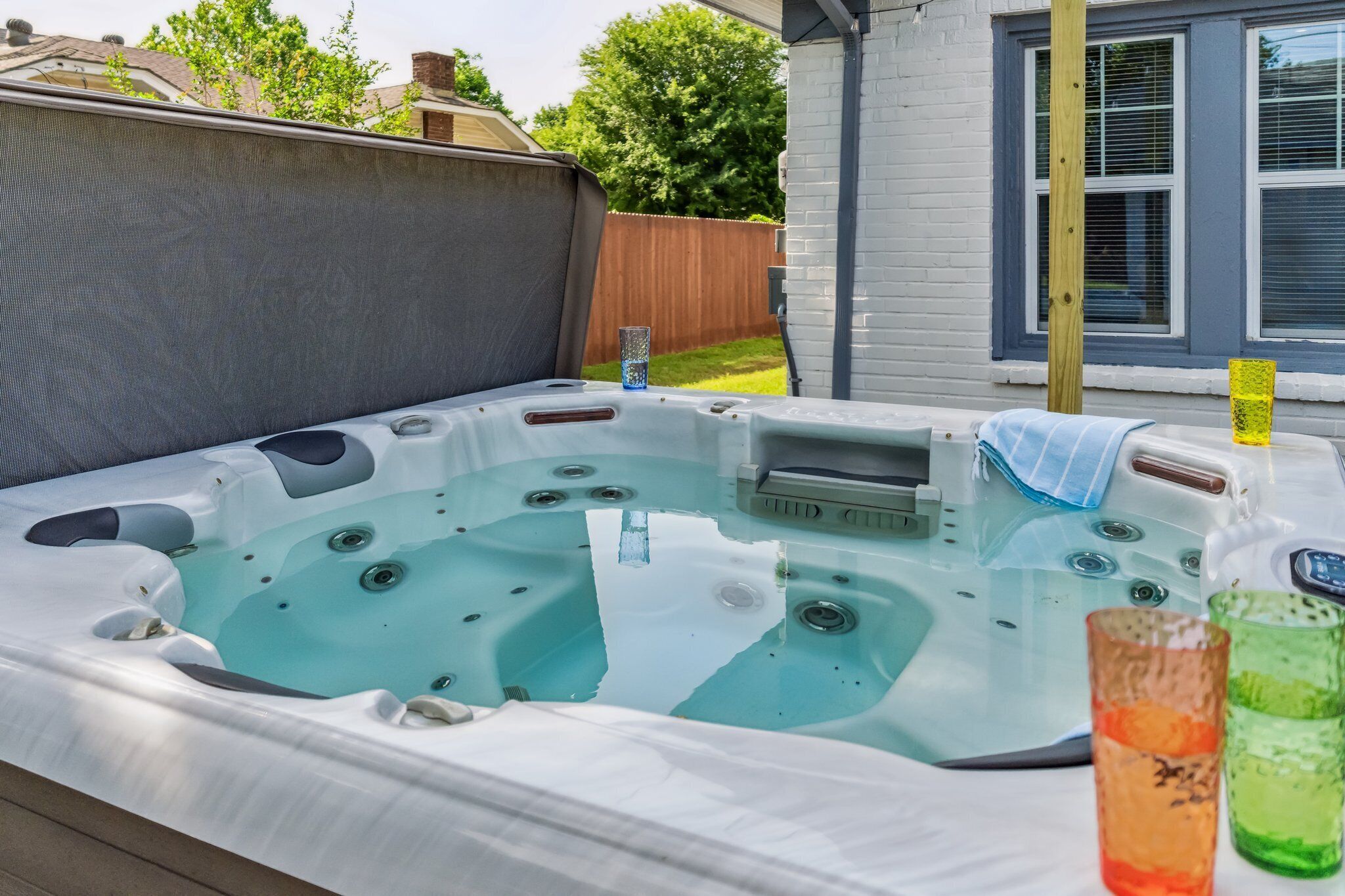 Un jacuzzi con panel de control, una toalla y dos vasos de agua.