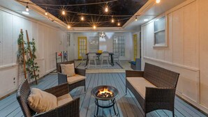 A cozy patio with wicker furniture, a fire pit, and string lights. - Mini Golf | Pool | Game room | Stylish & Spacious | Wifi | Free Parking (Dallas)