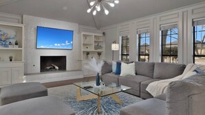 A modern living room with a fireplace, a large flat-screen TV, and a glass coffee table. - Mini Golf | Pool | Game room | Stylish & Spacious | Wifi | Free Parking (Dallas)