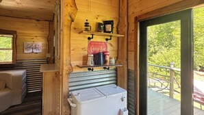 Ein gemütliches Blockhaus-Interieur mit einer Kaffeebar, einem Schild für Olam Kaffee und Blick ins Freie.