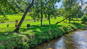 Ein ruhiger Park am Flussufer mit Picknickplatz und Bank.