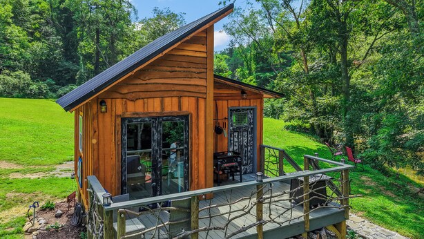Eine Holzhütte mit einer Veranda, umgeben von üppiger, grüner Landschaft.