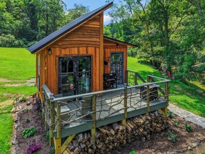 Une cabane en bois dotée d’une terrasse, entourée d’un paysage verdoyant luxuriant.