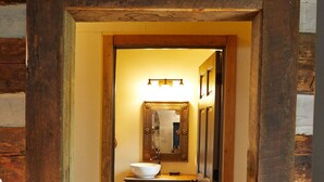 A wooden hallway leading to a bathroom with a sink, mirror, and wooden cabinets.