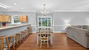 A modern kitchen with wooden stools, a dining table, and a chandelier. - MN 4872-101 | Beautiful Myrtlewood Golf Villa | Myrtle Beach (Myrtle Beach)