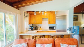 A modern kitchen with wooden cabinets, stainless steel appliances, and a large window. - Beach Villa (St. John's)