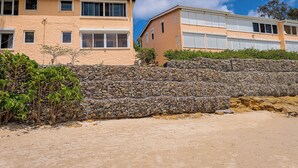 A building with multiple windows and a stone wall in the foreground. - Beach Villa (St. John's)