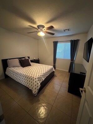 A bedroom with a bed, a ceiling fan, a window with curtains, a TV, and a dresser. - 4-bedroom house in welcoming Goodyear,AZ with WiFi, AC. Enjoy your stay (Goodyear)