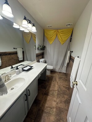 A bathroom with a white sink, a toilet, and a shower curtain with yellow and white patterns. - 4-bedroom house in welcoming Goodyear,AZ with WiFi, AC. Enjoy your stay (Goodyear)