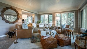 A spacious living room with a large mirror, leather ottomans, a coffee table, and a sofa. - The Bodhi: Spacious 5-bedroom retreat in Highlands with wooded mountain views. (Highlands)