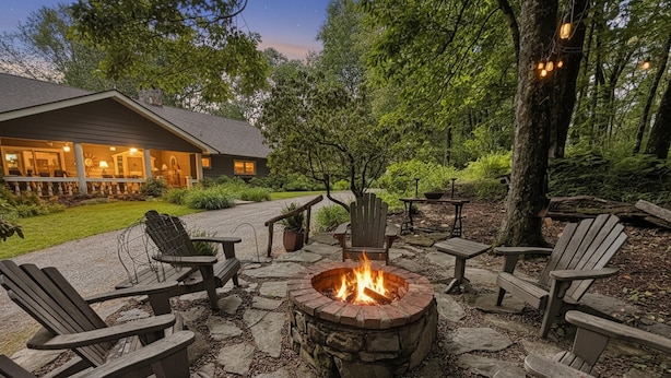 A stone fire pit surrounded by wooden Adirondack chairs and tables in a wooded outdoor area. - The Bodhi: Spacious 5-bedroom retreat in Highlands with wooded mountain views. (Highlands)