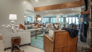 A spacious living room with a high ceiling, wooden beams, and a fireplace. - The Bodhi: Spacious 5-bedroom retreat in Highlands with wooded mountain views. (Highlands)