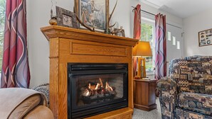 A cozy living room with a fireplace, patterned sofa, and curtains.