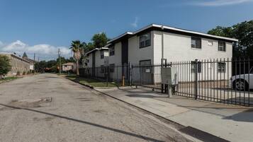 A residential street with a row of single-story houses, a sidewalk, and a parked car.