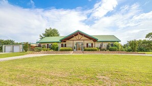 A two-story house with a green roof, a front porch, and a well-maintained lawn.