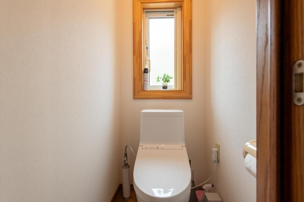 Une petite salle de bain avec des toilettes, une fenêtre et une porte en bois.