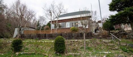 A modern two-story house with a wooden deck and a stone pathway leading to the entrance.