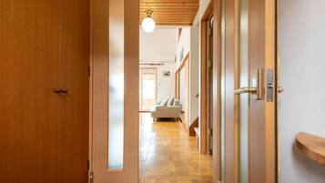 A wooden door leading into a hallway with a wooden floor and a light fixture above.