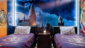 Ein Zimmer mit zwei Betten, Wandmalerei des Nachthimmels und Wappen von Hogwarts.