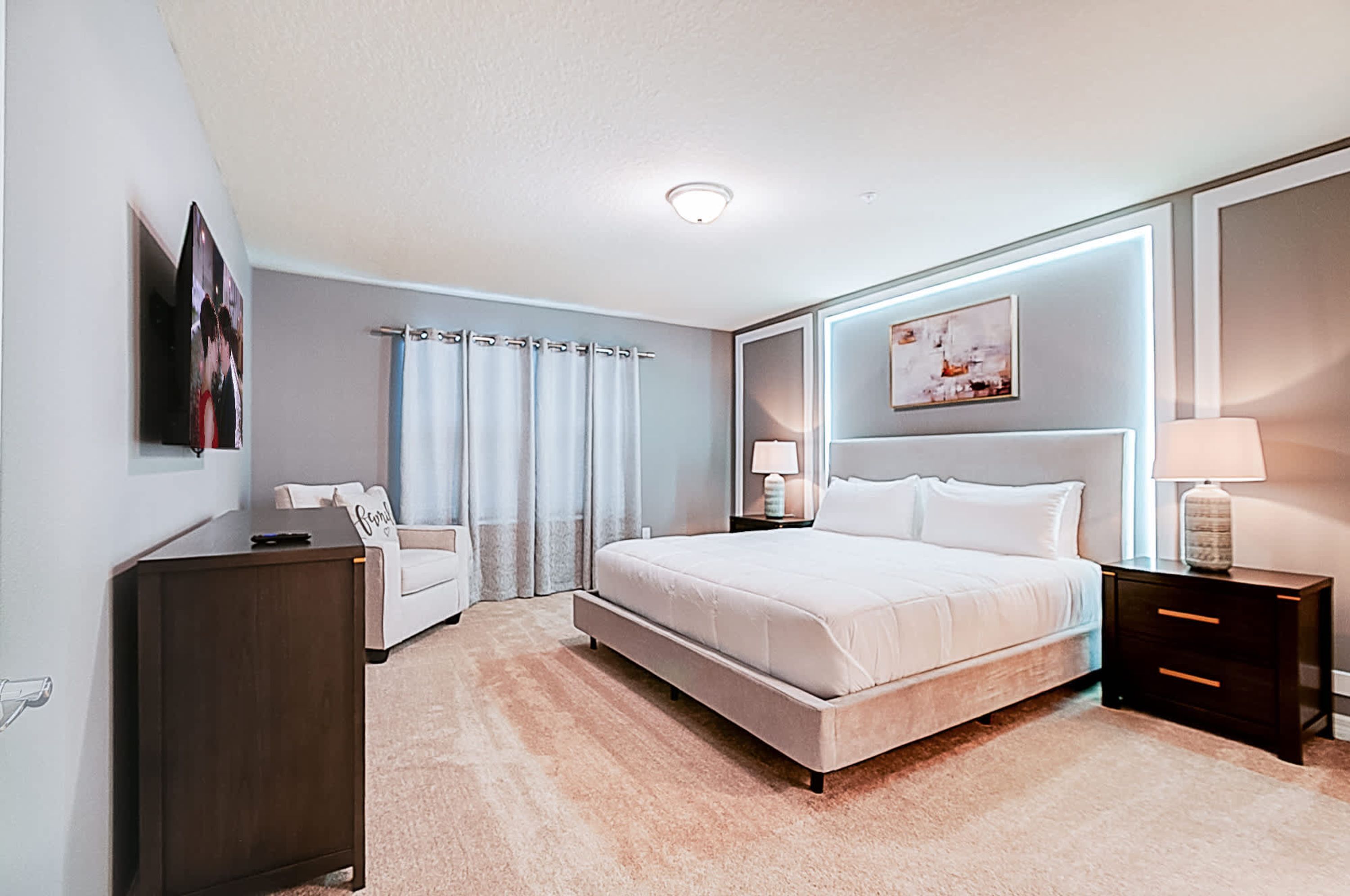 A modern bedroom with a large bed, bedside tables, a dresser, and a desk.