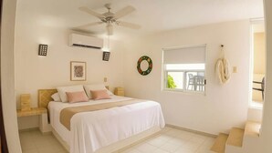 A bedroom with a bed, bedside tables, a ceiling fan, an air conditioning unit, a window with a view, and a wall-mounted light fixture. - Relax and Connect: Terrace + Nearby Beach (Playa del Carmen)