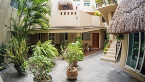 A courtyard with potted plants, a thatched-roof structure, and a staircase leading to an upper level. - Relax and Connect: Terrace + Nearby Beach (Playa del Carmen)