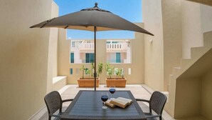 A balcony with a table, chairs, an umbrella, and potted plants. - Relax and Connect: Terrace + Nearby Beach (Playa del Carmen)