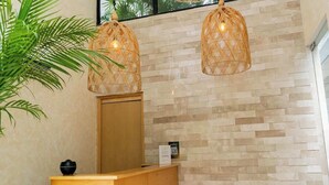 A reception desk with a wooden counter, a wall-mounted mirror, and two hanging wicker lamps. - Studio w/ Balcony | Pools, Gym, Steps to Beach (Playa del Carmen)