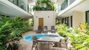 A hotel courtyard with a pool, lounge chairs, and potted plants. - Studio w/ Balcony | Pools, Gym, Steps to Beach (Playa del Carmen)