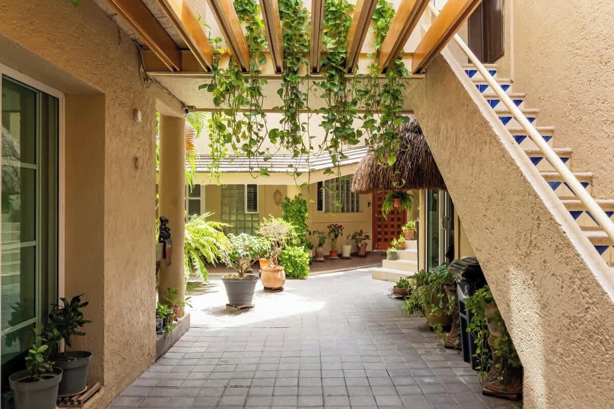 A covered outdoor area with potted plants, a staircase, and a thatched roof structure.