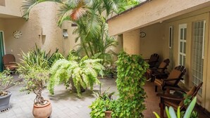 A courtyard with potted plants, outdoor seating, and a tiled floor.