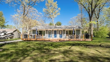 A single-story house with a porch, a deck, and a covered outdoor seating area.