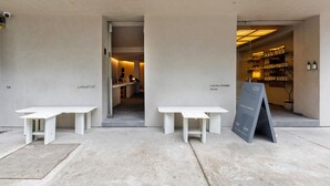 Een modern gebouw aan de buitenkant, met twee witte tafels en een zwart naambord.