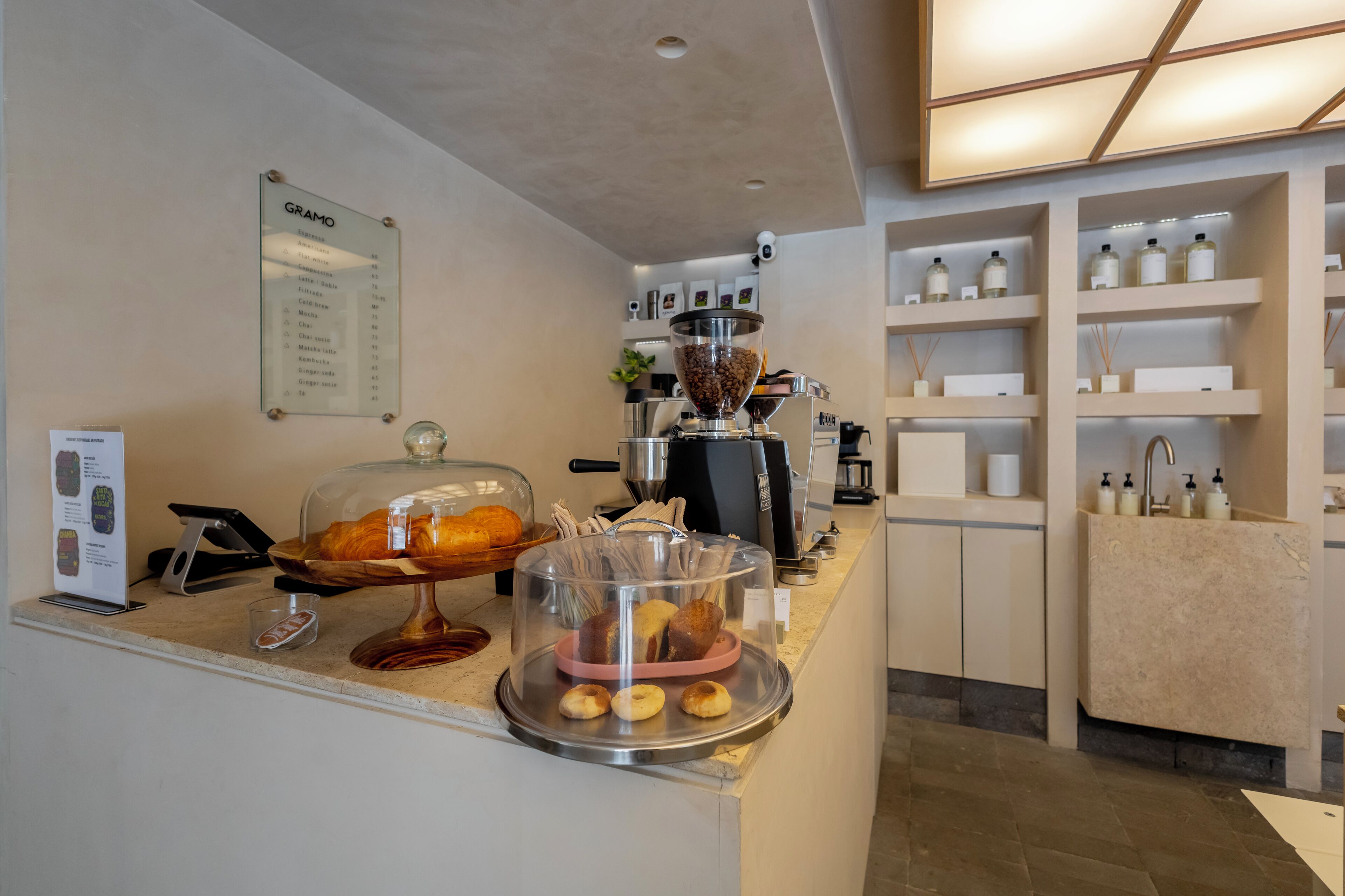A hotel reception area with a coffee machine, a menu board, and a display of pastries.