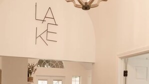 A spacious living area with a white couch, a chandelier, and a door with a white frame. - Lake Blackshear Retreat! (Cordele)