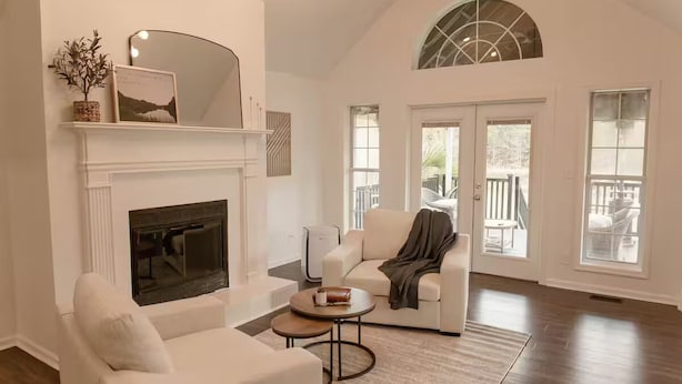 A spacious living room with a fireplace, white furniture, and large windows. - Lake Blackshear Retreat! (Cordele)