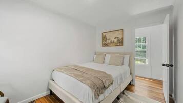 A bedroom with a bed, a door, and a window.