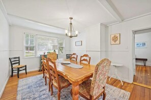 A dining area with a wooden table, six chairs, and a chandelier. - Spacious Central Berkshires Home for Groups (Lee)