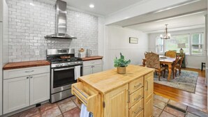 A kitchen with white brick backsplash, stainless steel appliances, wooden cabinets, and a wooden island. - Spacious Central Berkshires Home for Groups (Lee)