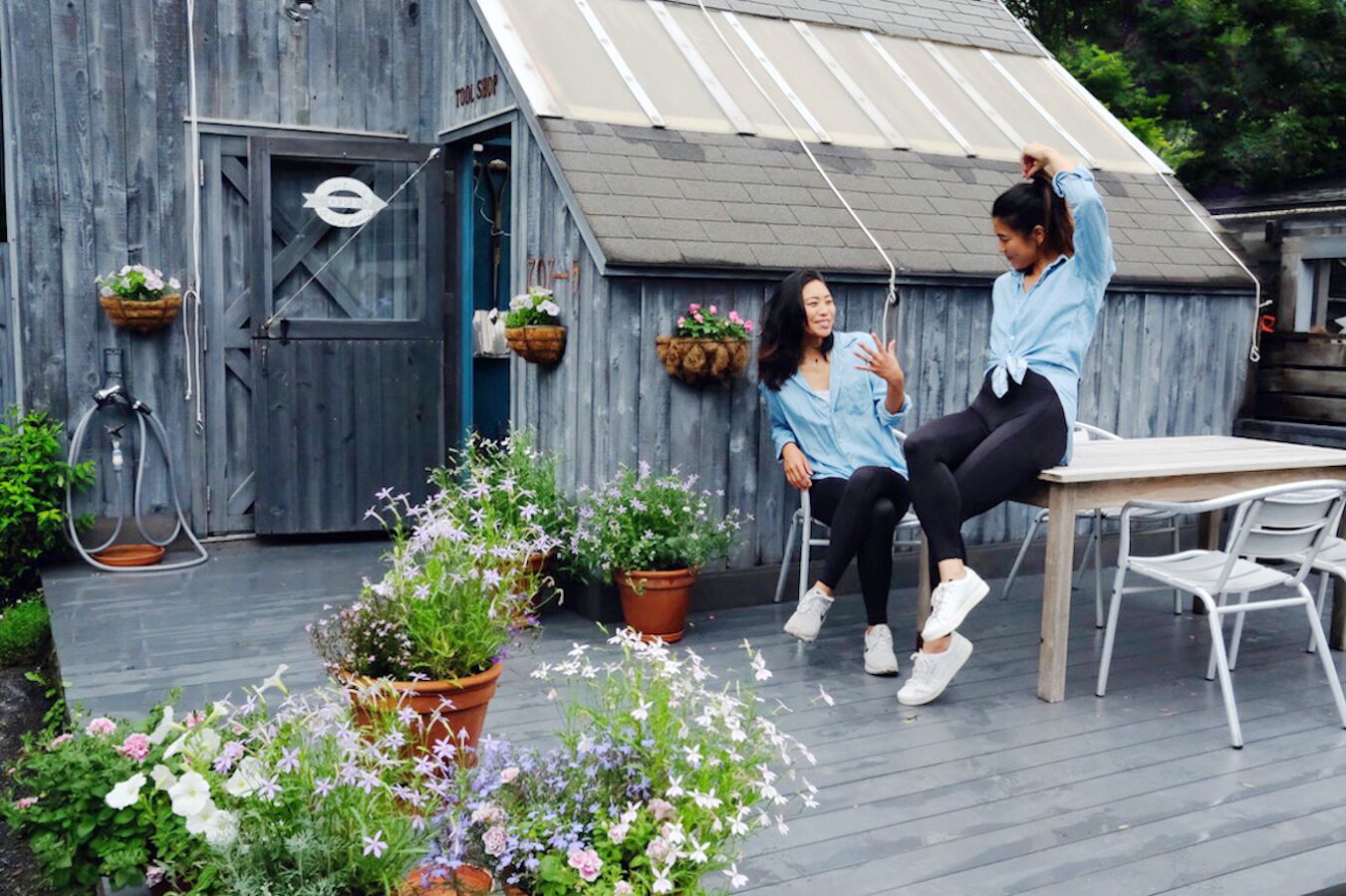 A rustic wooden building with a metal roof, a door with a sign, and potted plants.