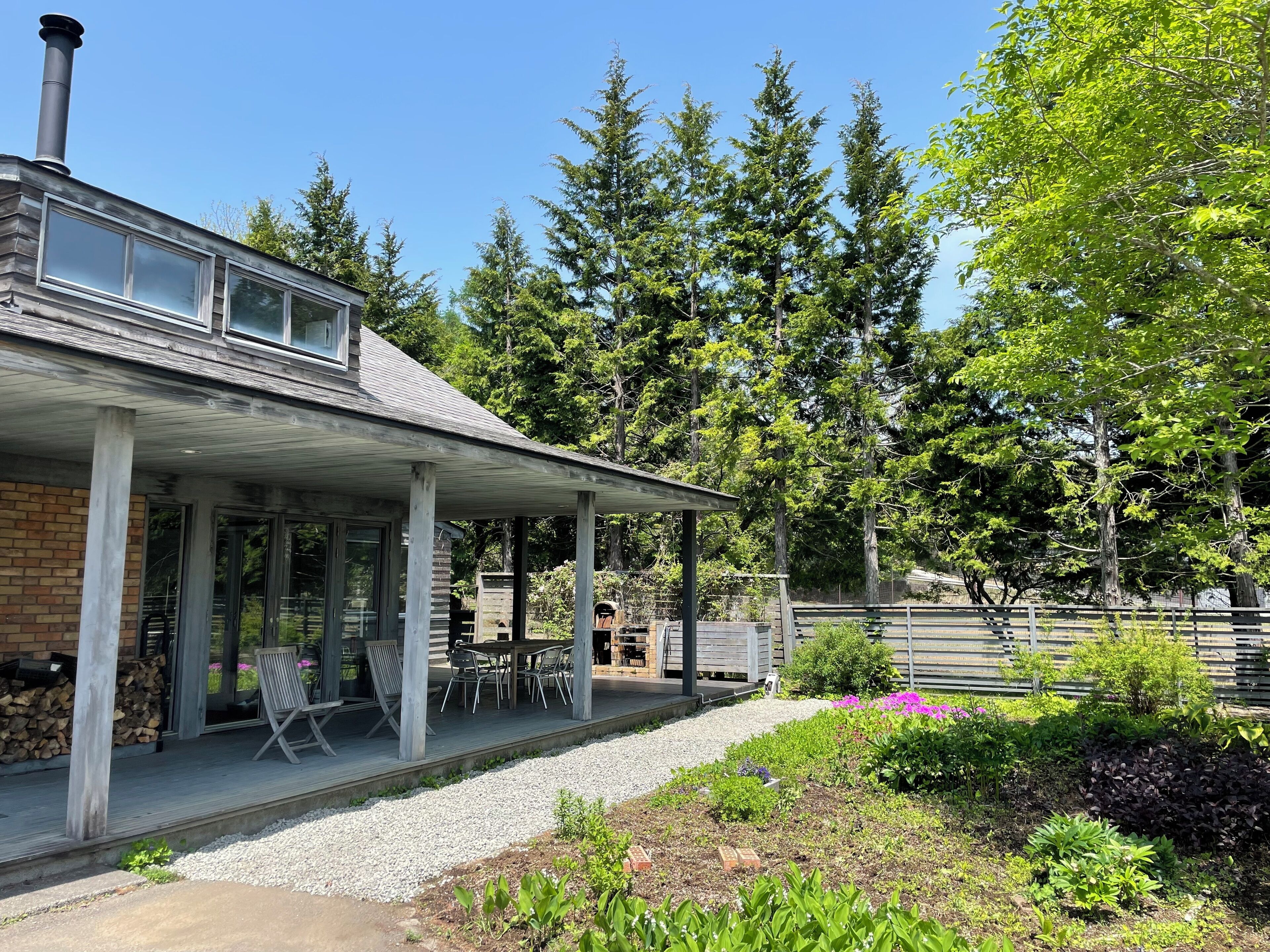 A house with a covered porch, outdoor seating, and a garden.