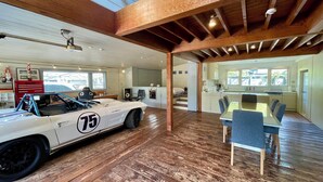 A spacious room with a classic race car, wooden flooring, a dining area, and a kitchen. - GARDEN SHED (Yamanakako)