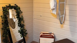 Una stanza angolare con una panca, uno stendibiancheria, una valigia e una ghirlanda decorativa.