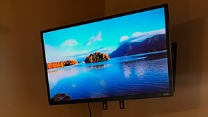 Un angolo cottura compatto con forno a microonde, macchina del caffè e televisione a parete che mostra un paesaggio suggestivo.