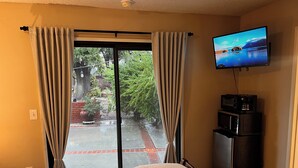 Una camera d'albergo con un letto, una televisione, un frigorifero e una porta scorrevole in vetro che dà su un patio.