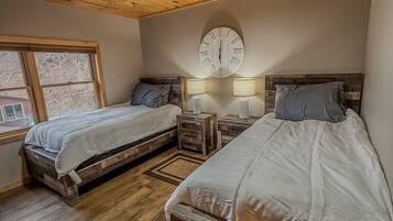 Une chambre avec deux lits en bois, un ventilateur de plafond, une horloge murale et une fenêtre.