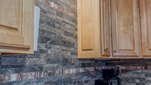 Eine Küche mit zwei Edelstahl-Spülen, Holzschränken und einer Spritzschutzwand mit gemusterten Fliesen.