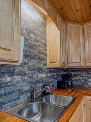 A kitchen with two stainless steel sinks, wooden cabinets, and a backsplash with patterned tiles.