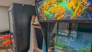 Ein Vintage-Spielautomat mit Lenkrad und Bildschirm, der ein Rennspiel zeigt.